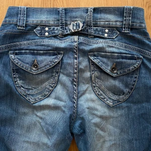Lindex Jeans  - Snygga blå jeans från Lindex, köpt för många år sen.  med coola detaljer och fina knappar fram och ficklock med knapp bak. Jeansen har en klassisk straight passform med coola bakfickor. Jeansen hade hål förut men har fixat det hos skräddaren. Ni kan se på bilden hur det ser ut innanför och utanför. Det syns inget utanför. Och märks inget. Men kan kännas lite tajt när du har på dig den eftersom den är sydd. Därför jag rekommenderar till någon som har storlek XS. Möts i Stockholm! Fraktar inte 🌸💕