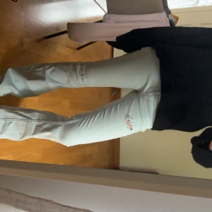 Ljusblå bootcut jeans med slitningar - Säljer ett par ljusblå jeans med bootcut passform och snygga slitningar på låret och vid fickan. Materialet är mjukt denim och färgen är i en snygg ljusblå. Jeansen har gåt sönder lite på insidan av ena låret men har sytts igen och syns knappt. Storlek 24/32