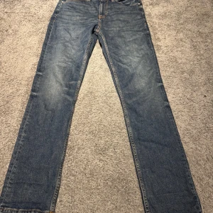 Blå jeans från NN07 Johnny 1839 - Säljer ett par klassiska blå jeans från NN07, modell Johnny 1839. Jeansen har rak passform, fem fickor och snygga kontrastsömmar. Materialet är slitstarkt denim i bomull och färgen är mörkblå med lätt tvättade detaljer. Perfekt för dig som gillar stilrena och tidlösa jeans.