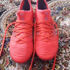 Röda Puma Future fotbollsskor - Säljer ett par grymt snygga Puma Future fotbollsskor i röd färg med blå detaljer. Skorna har coolt mönstrad ovandel och snörning för bästa passform. Lätta och smidiga med platt sula, perfekta för dig som vill sticka ut på planen. Vi kan diskutera prison om du vill