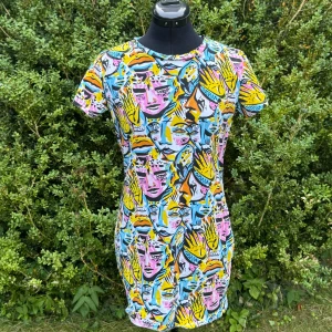 Färgstark kort klänning från Monki - Säljer en supercool kort klänning från Monki med ett unikt ansiktsmönster i blått, gult, rosa, orange och svart. Klänningen har rund hals, korta ärmar och är gjord i mjuk bomull. Perfekt för dig som gillar färg och statement-plagg!