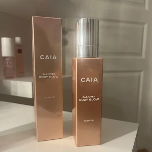 CAIA All Over Body Glow  - CAIA All Over Body Glow i färgen Golden Tan ger huden en snygg, solkysst lyster. Kommer i en lyxig fyrkantig flaska med silvrig pump och matchande förpackning. Perfekt för att boosta glow på kroppen med en gyllene finish. (Aldrig använd, den här färgen säljs inte längre) Nypris: 495 kr