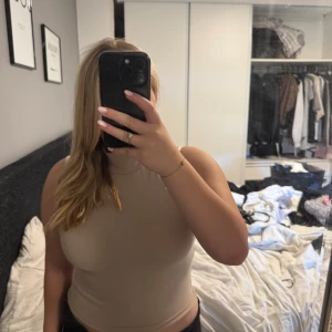Beige polotopp från Gina Tricot - Säljer en beige polotopp från Gina Tricot i storlek M. Toppen är ärmlös med hög krage och har en clean, slim passform. Materialet är mjukt och stretchigt, perfekt för att styla med jeans eller kjol. Enkel och snygg basic som funkar till många looks.