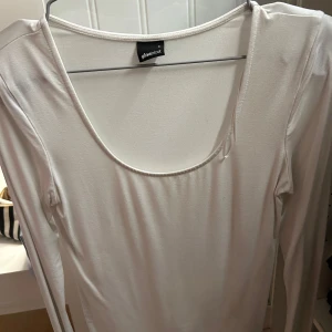 Vit långärmad topp från Gina Tricot - Säljer en stilren vit långärmad topp från Gina Tricot med rundad halsringning. 