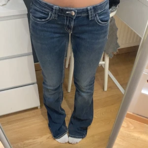 Blå bootcut jeans med broderade fickor - Har små hål nere vid foten men inget som syns!!  Snygga blå jeans med bootcut passform och låg midja. Baksidan har coola broderade detaljer på fickorna som ger extra stil. 