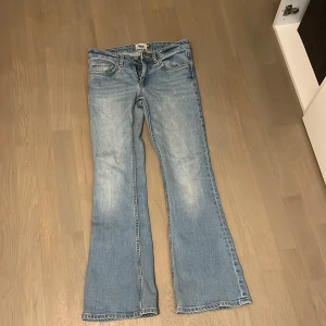 Bootcut jeans i ljusblå denim från 157 - Bootcut jeans från lager 157 i ljusblå tvättad denim. Modellen är lågmidjad med klassiska fem fickor och dragkedja. Jeansen har en snygg bootcut-passform som ger en perfekt vibe och är perfekta för dig som gillar att ha jeans till vardags. Materialet är mjukt och bekvämt bomullstyg.