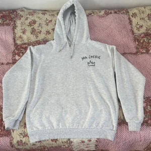 Grå hoodie med tryck Ma Chérie - Säljer en ljusgrå hoodie med huva och snörning, samt trycket 'Ma Chérie' och en krona på bröstet. Tröjan har ribbade muddar vid ärmslut och nederkant, perfekt för chill dagar. Materialet känns mjukt. Pris kan diskuteras då jag vill bli av med den fort💗