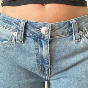 True Religion ljusblå bootcut jeans - Säljer ett par ljusblå jeans från True Religion med klassisk U-söm på bakfickan och logopatch. Jeansen har bootcut passform, låg midja och snygga detaljer med silverfärgade knappar. Perfekt för dig som gillar street och retrovibe.