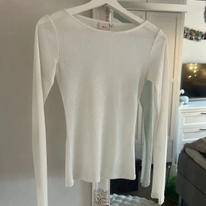 Vit långärmad tröja från Nelly - Snygg vit långärmad tröja från Nelly i storlek S. Tröjan har en enkel och clean design med rund hals och smal passform. Perfekt att styla med jeans eller kjol för en fräsch look. Materialet känns mjukt och lätt mot huden.
