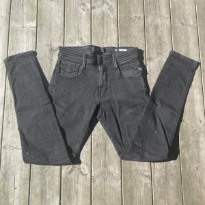 Replay Anbass svarta jeans - Svarta Replay Anbass jeans med klassisk femficksdesign och snygga detaljer på bakfickorna. Jeansen är tillverkade i stretchigt denim för extra komfort. Perfekta för dig som gillar stilrena och moderna jeans. Enda defekten är på ena bakfickan där det är en liten missfärgning. Om ni har några frågor så är det bara att höra av er!😁