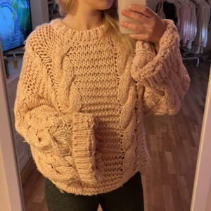 Oversized rosa stickad tröja - Supermysig oversized stickad tröja i beige med grova flätor och breda muddar. Tröjan har lång ärm och chunky känsla, perfekt för att hålla sig varm och se chill ut. Passar dig som gillar en loose fit och vill ha en cozy vibe i höst och vinter.