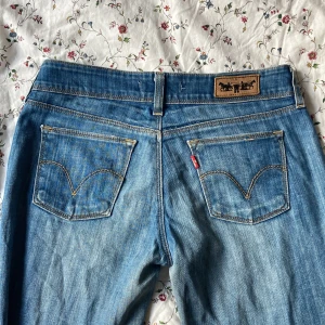 Levis 479 bootcut jeans blå - Säljer ett par klassiska Levis 479 jeans i ljusblå tvätt. Modellen har låg midja och bootcut-ben, med snygga slitningar och typiska Levis-detaljer som läderpatch och röda etiketten. Perfekta för dig som gillar retrovibbar och avslappnad stil. Passar storlek S 
