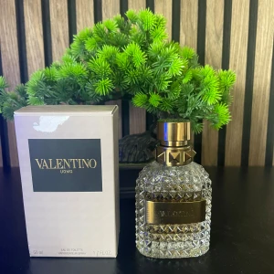 Valentino Uomo Eau de Toilette 50ml - Lyxig herrparfym från Valentino i en snygg, kristallmönstrad glasflaska med guldfärgade detaljer och nitar på korken. Doften är elegant och flaskan känns exklusiv med sin guldiga etikett. Kommer i originalkartong.