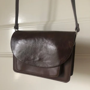 Brun axelväska i skinn med dragkedja - Snygg brun axelväska i skinn med justerbar rem och flera fack, inklusive ett med dragkedja. Aldrig använd❤️‍🔥