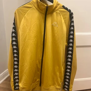 Kappa track jacka - Gul track jacket från Kappa. Storlek L/XL. Gott skick. den är lite nopprig vid ena fickan men inget man tänker på.