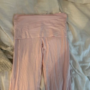 Ljusrosa mjukisbyxor från Gina Tricot - Supermjuka ljusrosa mjukisbyxor från Gina Tricot med bred, vikt midja och bootcut ben. Perfekta för chill dagar hemma eller när du vill vara extra bekväm. Tillverkade i skönt bomullsmaterial.