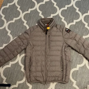 Ligthweigth jacket from parajumpers - Snygg beige dunjacka från Parajumpers med klassisk patch på ärmen och gul detalj vid kragen. Jackan har quiltad design, hög krage och flera dragkedjeförsedda fickor. Perfekt för kyliga dagar och riktigt lätt att bära.