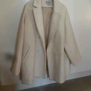 Beige kappa från NA-KD - Stilren beige kappa från NA-KD med dubbelknäppning och klassisk krage.