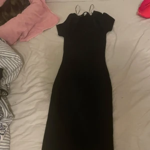 Svart långklänning med kort ärm - En stilren svart långklänning med korta ärmar och rund halsringning. Klänningen har en figurnära passform som ger en snygg siluett. Perfekt för dig som gillar en klassisk och enkel look.