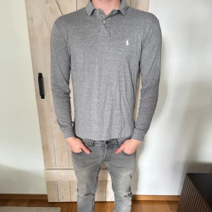Grå långärmad pikétröja från Ralph Lauren - Säljer en stilren grå långärmad pikétröja från Ralph Lauren. Storleken är M och skickar är mycket bra.