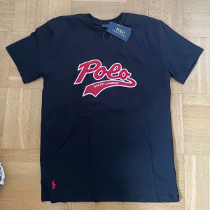 Ralph Lauren t shirt - Svart t-shirt från Polo Ralph Lauren med stort broderat rött och vitt Polo-logo på bröstet. Klassisk passform med rund hals och korta ärmar.  Helt ny aldrig använd. Kan gå ner i pris vid snabb försäljning 