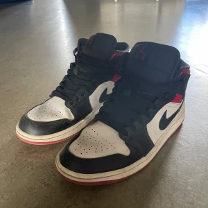 Nike Air Jordan 1 Mid svart/vit/röd - Säljer ett par Nike Air Jordan 1 Mid med klassisk svart, vit och röd färgkombination. Storlek 42,5, kan ordna en tvätt på dom. Kommer även i röda skosnören bredvid 