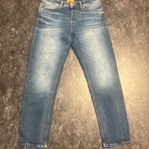 Blå jeans med ljusa slitningar w32l32 - Säljer ett par klassiska blå jeans med snygga ljusa slitningar framtill och baktill. Jeansen har raka ben, fem fickor och normal passform. Perfekta till sneakers och hoodie för en avslappnad look.