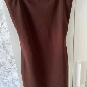 Brun klänning - Tight mörkbrun klänning som slutar lite under rumpan. Den är simpel men den är enkel att klä upp. Säljer då den är för liten för mig. Vid frågor eller behov av fler bilder hör av dig!