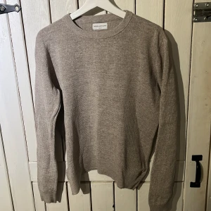 Beige stickad tröja These Glory Days - Snygg beige stickad tröja från These Glory Days i storlek medium. Tröjan har rund halsringning och långa ärmar, perfekt för lager-på-lager. Den neutrala färgen gör den enkel att matcha med olika outfits.