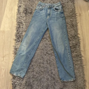 Never Denim 90s straight jeans blå - Snygga 90s straight jeans från Never Denim i klassisk ljusblå tvätt. Modellen har raka ben, och fem fickor. Perfekta för dig som gillar en avslappnad och tidlös look. Tillverkade i bomull för skön känsla hela dagen.