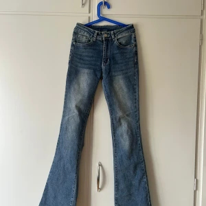 Bootcut jeans med broderade fickor Shein XS - Blå bootcut jeans från Shein i storlek XS med snyggt slitna detaljer och broderade bakfickor med nitar. Jeansen har klassisk femficksdesign och är tillverkade i bomull, polyester och lite stretch för skön passform.