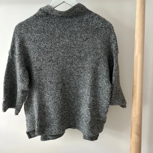 Grå stickad polotröja från Zara - Mysig gråmelerad stickad polotröja från Zara med italienskt garn. Tröjan har en hög krage och trekvartsärmar. Den är loose fit.