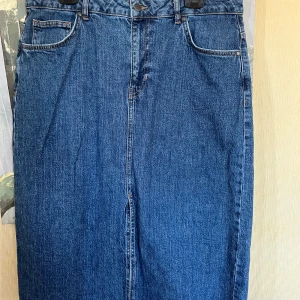 Blå raka jeansbyxor med klassisk look - Snygg blå jeanskjol i klassisk rak modell med fem fickor och bälteshällor. Kjolen  har en mörkblå tvätt och är tillverkade i robust denim. Perfekta för dig som gillar en tidlös och enkel stil.