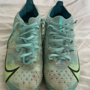 Nike Mercurial fotbollsskor turkos - Säljer ett par Nike Mercurial fotbollsskor i turkos med svarta och neongula detaljer. Skorna har snörning, låg profil och är tillverkade i syntetmaterial med meshstruktur för bra ventilation. Perfekta för dig som vill sticka ut på planen.