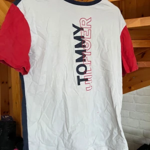 Tommy Hilfiger t-shirt i färgblock - Snygg t-shirt från Tommy Hilfiger med vit framsida, marinblå baksida och röda ärmar. Stor logga i svart och rött framtill. Klassisk rund halsringning och cool färgblock-design. Perfekt för dig som gillar streetstyle och märkeskläder. Den används aldrig och knappt någonsin kommit till användning. Stryks och tvättas innan frakt skriv vid frågor eller köp direkt😁♥️