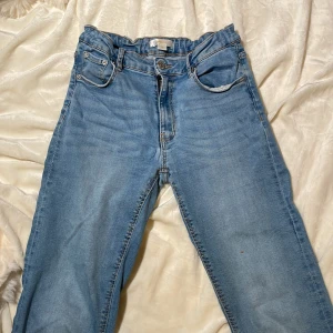 Jeans från Gina Tricot - Ett par blåa jeans från Gina tricot. Midwaist. En liten fläck på benet som man själv får avgöra hur tydlig den är. Lite slitna nere vid foten. Dem är utsvängda. Barnstorlek 158.