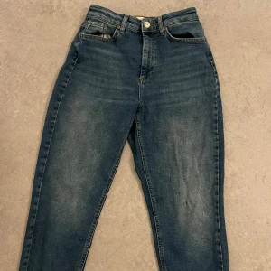 Blå högmidjade jeans från ONLY - Snygga blå jeans från ONLY med hög midja och klassisk femficksdesign. Jeansen har en rak passform och är tillverkade i slitstarkt denimtyg. Perfekta för dig som gillar en enkel och tidlös look.