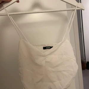 Vit linnetopp från Bik Bok - Supersöt vit linnetopp från Bik Bok med tunna axelband och smockad rygg. Toppen har en lätt v-ringning framtill och är gjord i ett mjukt, tunt tyg som känns luftigt. Perfekt för varma dagar och enkel att styla med jeans eller kjol.