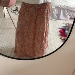 Blommig rosa långkjol från Marta - Supersöt långkjol från Marta i en ljusrosa ton med blommigt mönster i vitt, gult och grönt. Kjolen har smock i midjan för en bekväm passform och är gjord i ett luftigt linnetyg. Köpt förra sommaren från Lululia. Inga defekter pris kan diskuteras!! Storleken är onesize men passar ungefär S