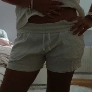Lågmidjade Vita linne shorts - Snygga vita shorts med elastisk midja och snörning framtill. De är tillverkade i ett lätt och skönt bomullstyg, perfekta för varma dagar. Shortsen har en bakficka. Nypris 150. På bilden är dem en aning skrynkliga men går att strykas. Storlek 160 (barn men dem är väldigt stretchiga.. Säljer pga att jag har ett par likadana