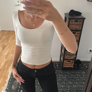 Vit croppad topp med öppen rygg - Säljer en vit croppad topp med rundad urringning fram och snyggt öppen rygg. Toppen är använd max 3 gånger och är i mycket bra skick! 