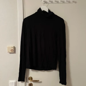 Svart polotröja från BikBok XL - En svart polotröja från BikBok i storlek XL. Tröjan har lång ärm och klassisk polokrage, perfekt för lager-på-lager. Tunt och mjukt material som känns skönt mot huden. Enkel och stilren design som funkar till många outfits. Katt finns i hemmet