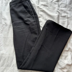 Svarta kostymbyxor från H&M, stl 34 - Snygga svarta kostymbyxor från H&M i storlek 34. Har sytt upp byxorna då de var lite långa för mig, men det går lätt att ändra tillbaka till ursprungsländen!!