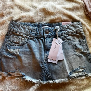 Ljusblå jeanskjol från Gina Tricot - Trendig ljusblå jeanskjol med låg midja från Gina Tricot. Kjolen har slitna detaljer, fransig nederkant och klassiska fickor både fram och bak. Perfekt för dig som gillar en edgy och avslappnad stil. Helt slutsåld!!!