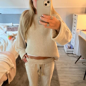 Beige croppad stickad tröja - Supermysig beige stickad tröja med croppad passform och breda ribbade muddar vid ärmslut och nederkant. Perfekt för lager-på-lager och chill dagar. Långärmad och riktigt skön att ha på sig.