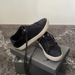 Svarta sneakers från Vagabond - Säljer ett par svarta sneakers från Vagabond med vit platt sula och snörning. Skorna har en stilren design i mocka och passar perfekt till en avslappnad look. Klassiska och enkla att matcha med olika outfits. Storlek 36. Nypris 1200kr säljer för 300krkan eventuellt gå ner 