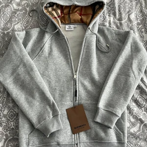 Grå hoodie från Burberry - Snygg grå hoodie från Burberry. Resellar denna hoodie. Storlek XL men liten i storlek. Passar som storleken mellan M och L.