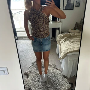 Leopardmönstrad one shoulder body - Säljer en snygg leopardmönstrad body från Zara med one shoulder-design och omlott-detalj. Toppen är figurnära och har en cool, asymmetrisk axelrem. Perfekt för dig som vill sticka ut med ett djurmönster och trendig passform.