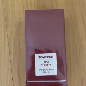 Tom Ford Lost Cherry EdP 100ml - Tom Ford Lost Cherry Eau de Parfum i en lyxig, mörkröd rektangulär kartong. Flaskan rymmer 100 ml och doften är känd för sina söta och fruktiga körsbärstoner. Perfekt för dig som gillar exklusiva och unika parfymer.