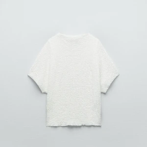 Vit strukturerad topp från Zara - Säljer en vit topp från Zara med korta ärmar och en snygg strukturerad yta. Modellen är boxig och perfekt till jeans eller kjol. Kommer inte till användning💕